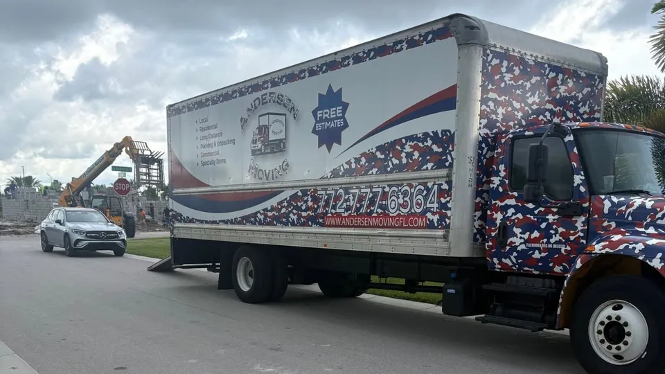 Andersen Moving box truck with its ramp down on a Port St. Lucie street beside a community under construction.